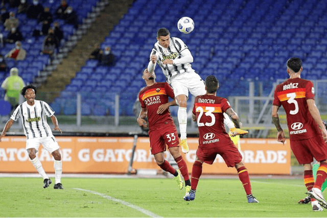 Cristiano Ronaldo, towering above Roma players, showcases his commanding height as he leaps to head a crucial ball for Juventus.
