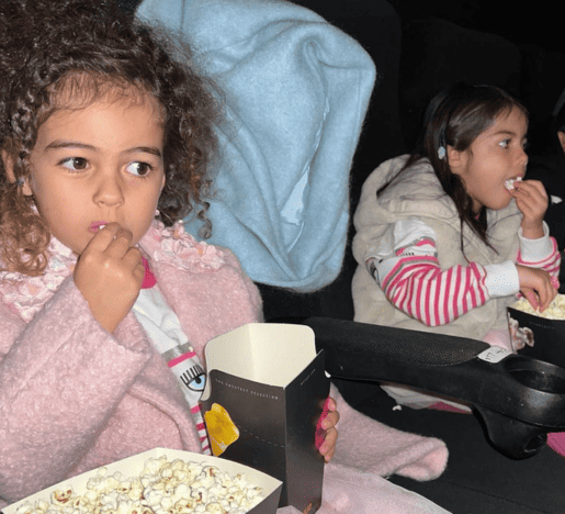 Eva, and Alana Martian eating popcorn while watching movie in a cinema.
