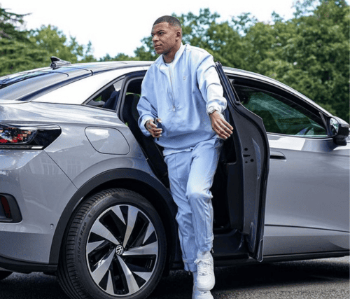 Kylian Mbappe stepping out of a car, exuding confidence and style, a moment of arrival captured in a snapshot.