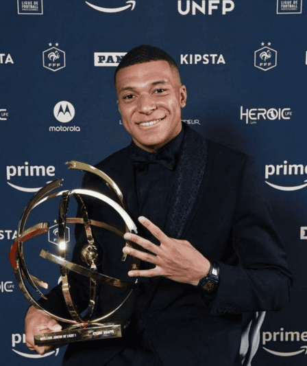 Kylian Mbappe grins with his Ligue 1 Player of the Year award, a testament to his exceptional skills and impact in the football realm.