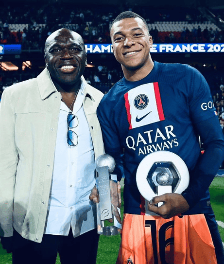 Kylian Mbappe and his father, a dynamic duo at the Parc des Princes, as Mbappe proudly showcases two individual awards, a scene of triumph and pride.