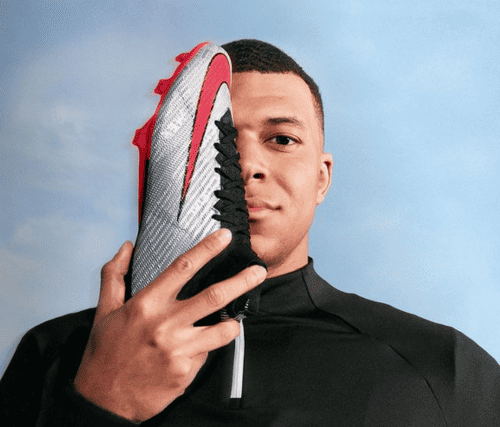 Kylian Mbappe proudly posing with his Nike Mercury cleats, a symbol of his exceptional partnership with Nike and prowess on the football stage.