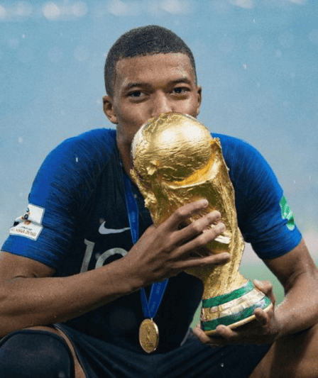Kylian Mbappe passionately kisses the World Cup trophy, a victorious moment symbolizing his excellence on the global football stage.